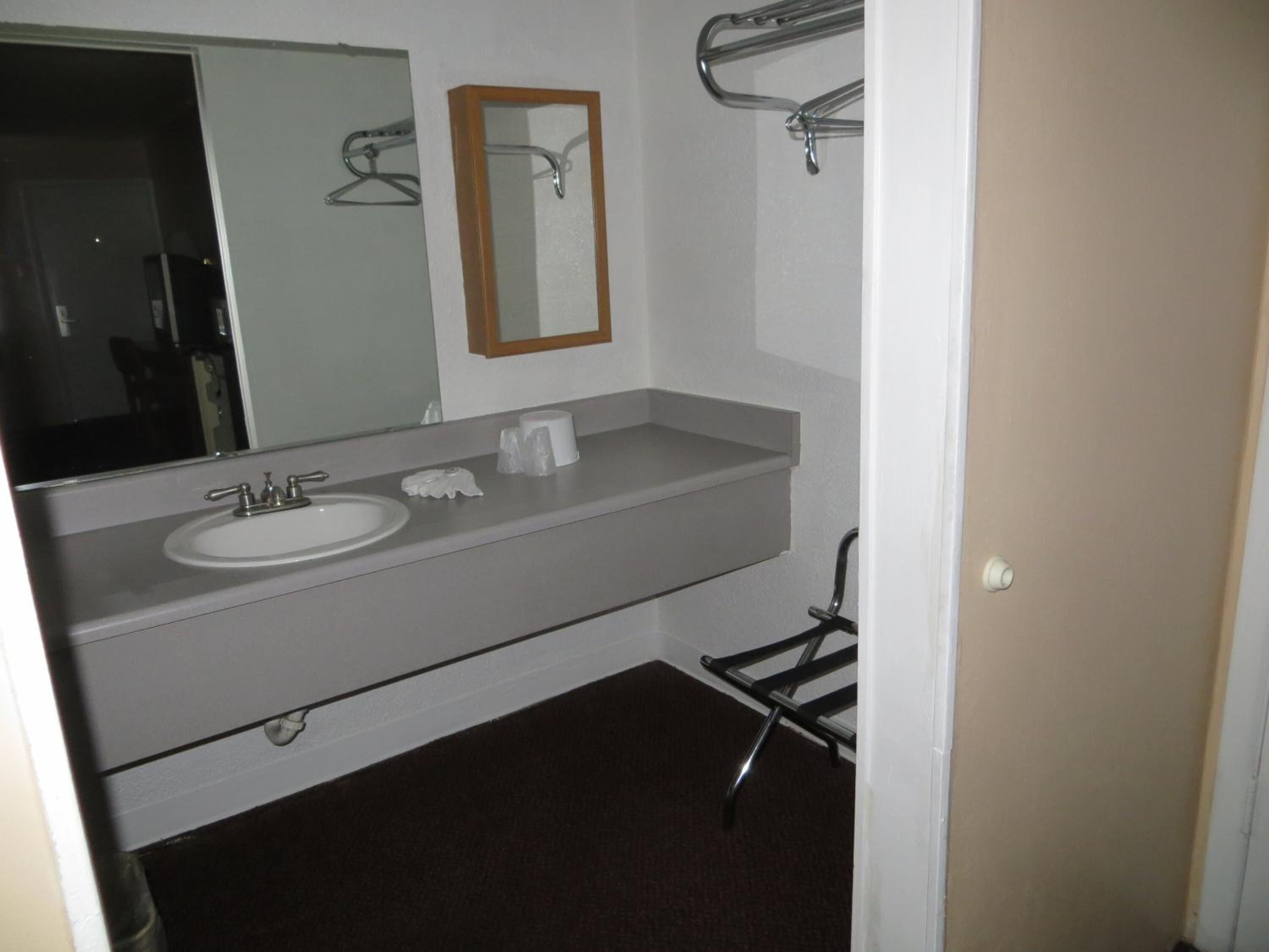 Un baño con lavamanos blanco, un espejo y un perchero para toallas.
