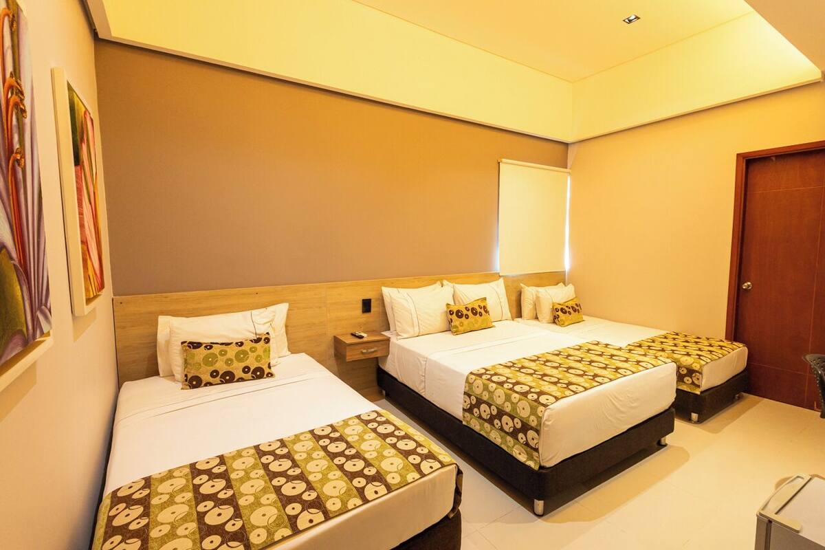 A hotel room with two beds, a wooden headboard, a nightstand, and a door.