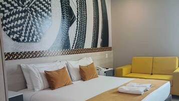 Una habitación de hotel con una cama, un sillón amarillo y una gran obra de arte abstracta en la pared.