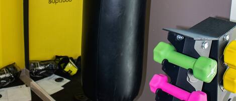 Un gimnasio con un saco de boxeo, mancuernas y equipo de ejercicio.
