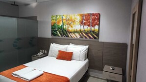 A modern hotel room with a bed, a nightstand, a painting, and a bathroom with a glass shower. - Hotel Santa Clara Boutique (Montería)