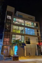 Un hotel moderno con varios pisos, grandes ventanales y una entrada bien iluminada.