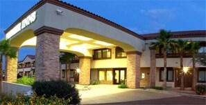 A hotel with a modern facade, featuring a prominent entrance with a covered walkway and palm trees. - Premier Inns Tolleson (Tolleson)