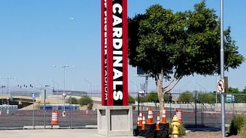 A tall sign with "ARIZONA CARDINALS" written on it, located at a sports stadium entrance.