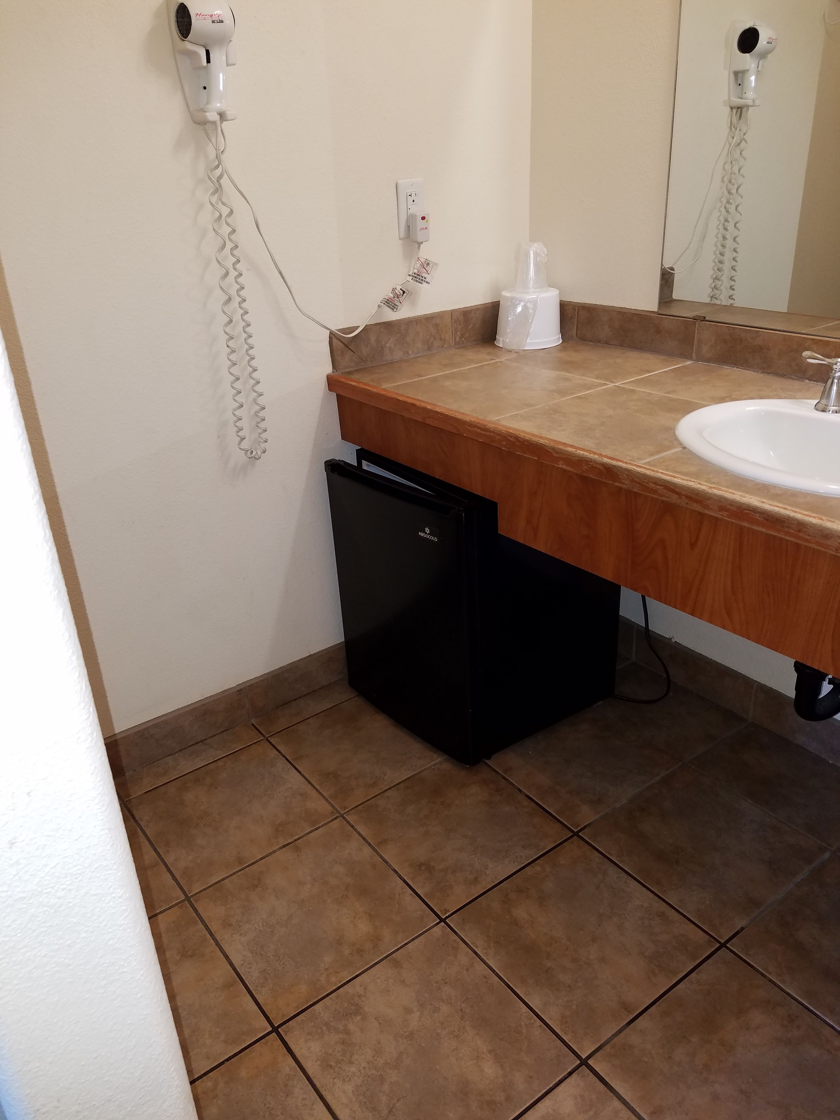 A bathroom with a wooden countertop, a white sink, and a black dishwasher.