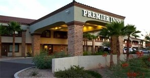 A hotel with a sign reading "Premier Inns" and a covered outdoor area with palm trees.
