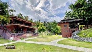 A resort with a two-story building, a thatched-roof structure, and a paved pathway. - 24/7 Lantawan Resort (Oslob)