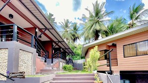 A resort with a stone facade, a covered staircase, and palm trees in the background. - 24/7 Lantawan Resort (Oslob)