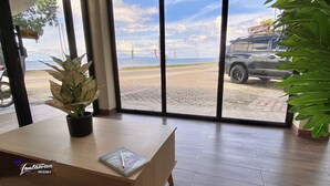 A reception desk with a notebook, a potted plant, and a view of a parking area with a vehicle and a sign for Tantawan Resort. - 24/7 Lantawan Resort (Oslob)