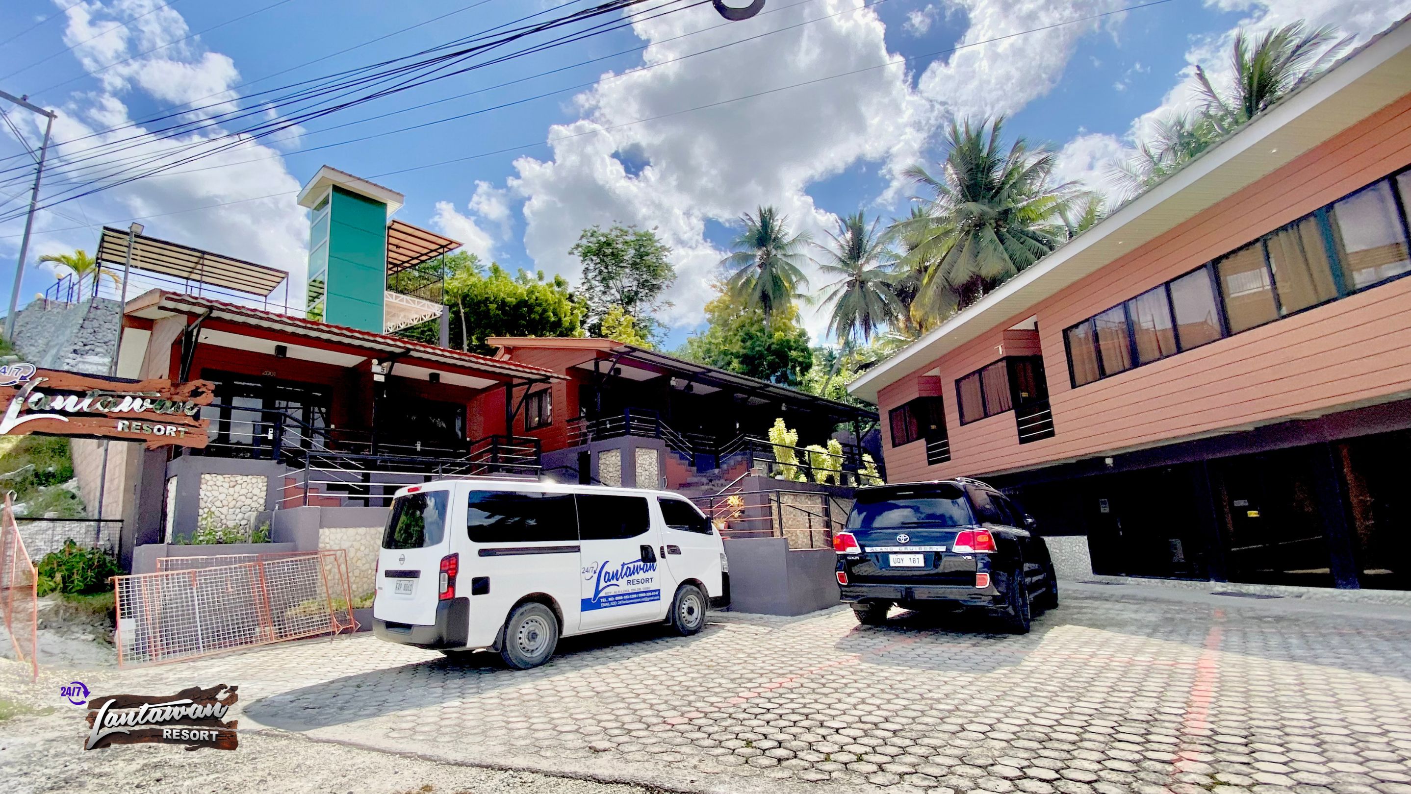 A white van and a black car parked in front of a building with a sign reading "Lantawari Resort".