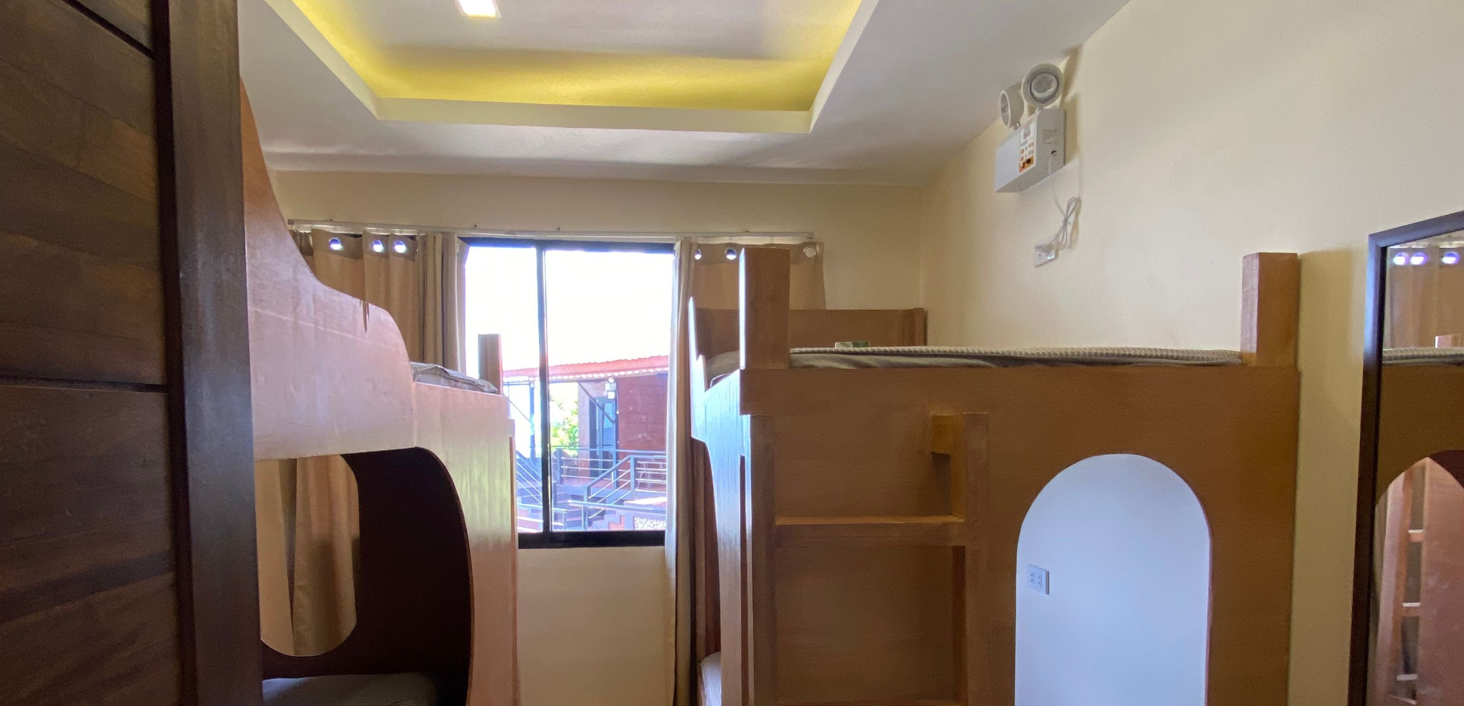 A room with bunk beds, a small window, and a ceiling light.
