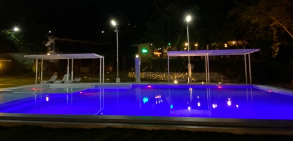 An outdoor swimming pool with blue lighting at Vantavan Resort.