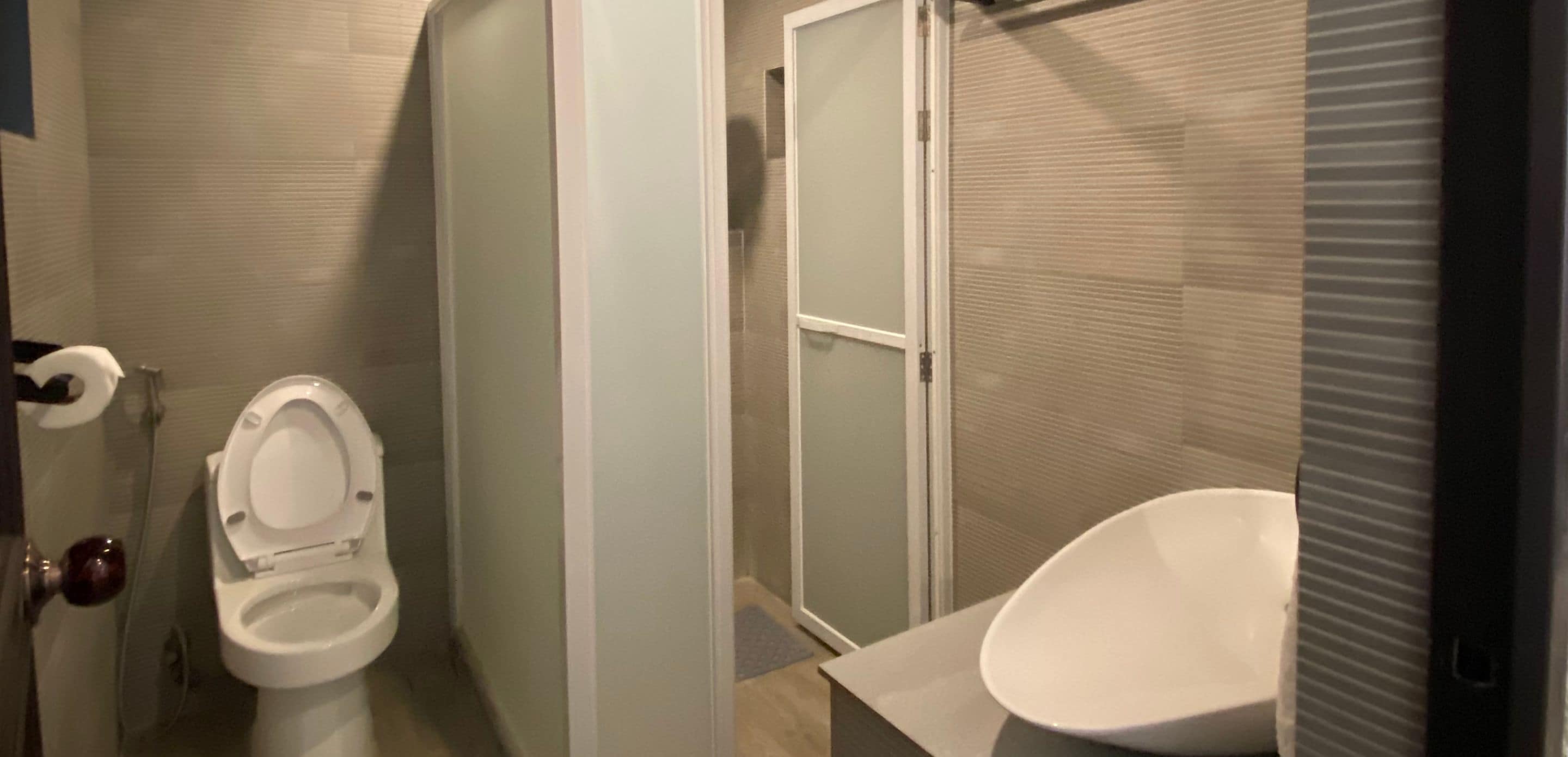 A bathroom with a toilet, a shower, and a sink.