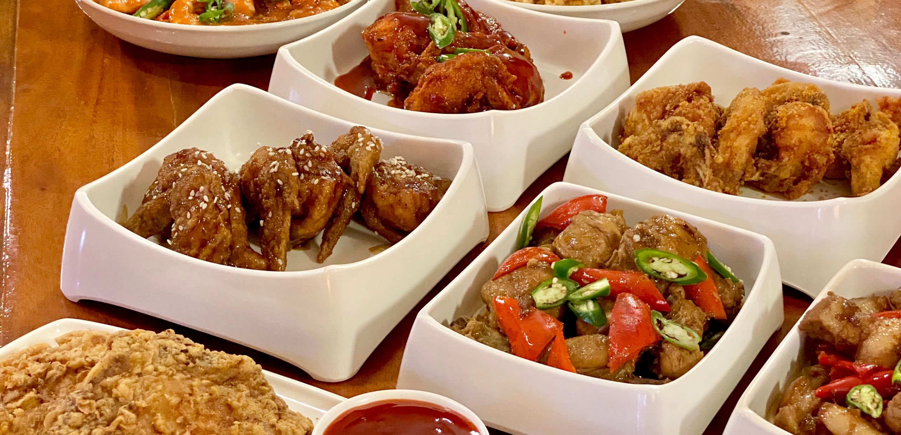A variety of dishes in white bowls on a wooden table.