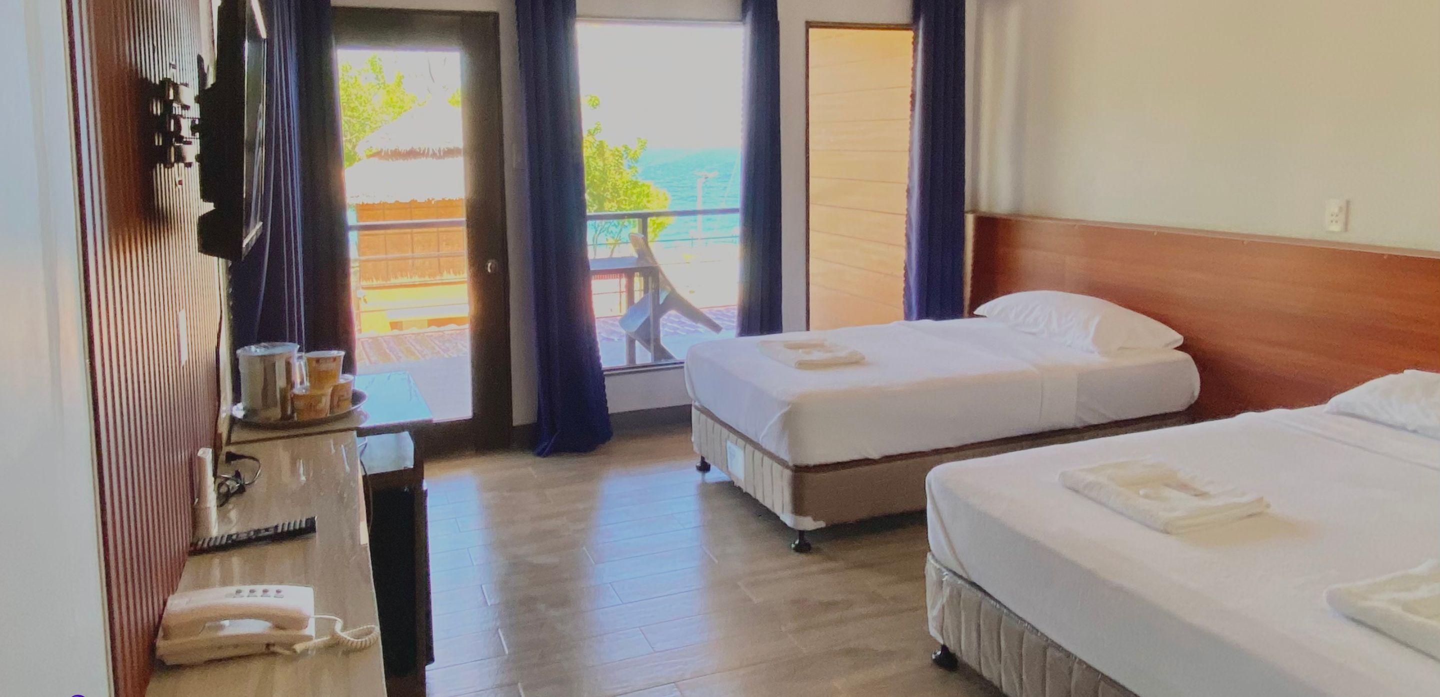 Een hotelkamer met twee bedden, een bureau met telefoon en uitzicht op het omliggende landschap.