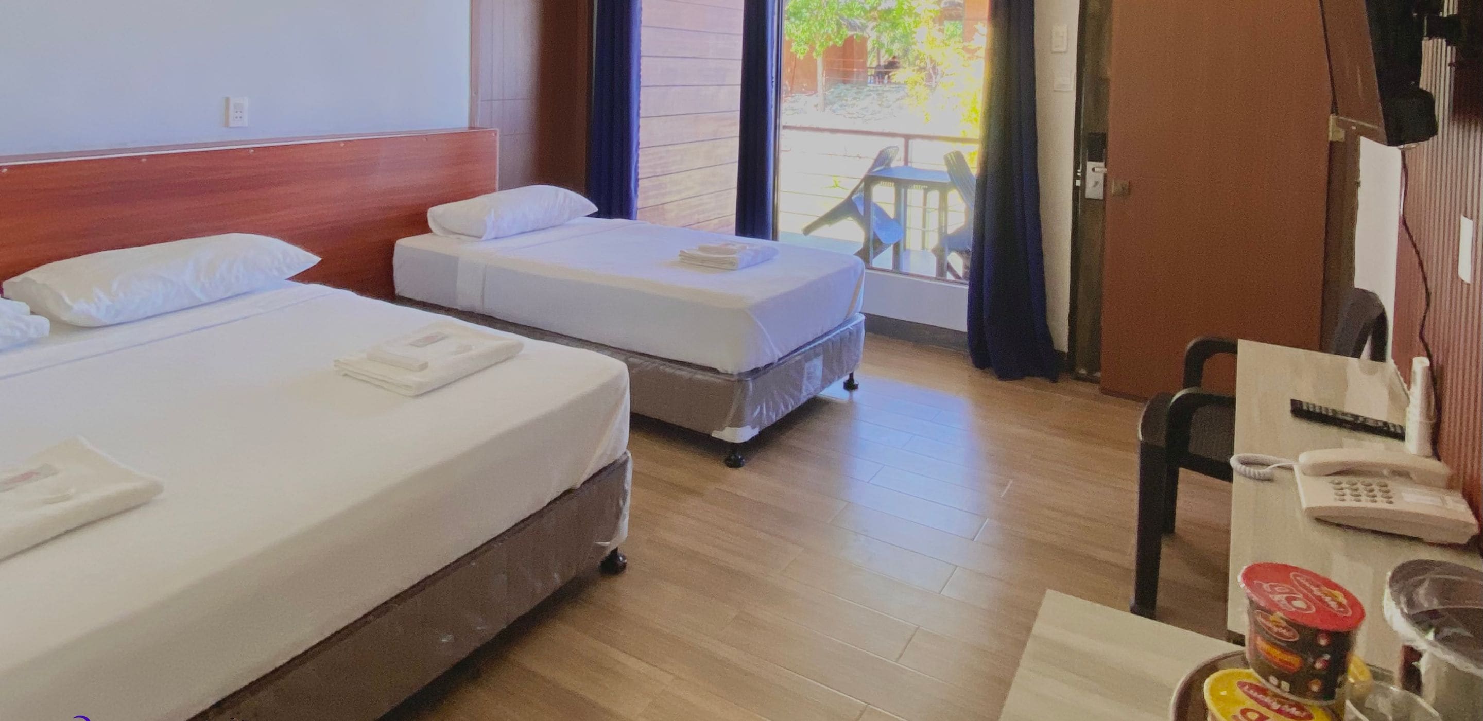 Een hotelkamer met twee bedden, een bureau met telefoon en een tafel met toevoegingen.