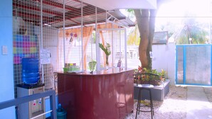 A kitchen area with a red counter, a water dispenser, and a sign listing soft drinks and snacks. - Pedz Cing Mango Lodge (Oslob)