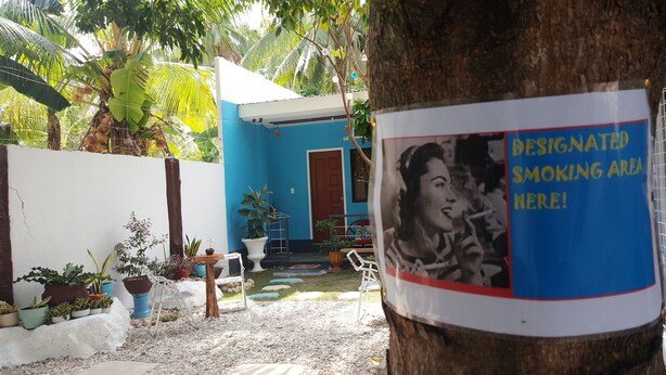 A blue house with a designated smoking area sign on a tree. - Pedz Cing Mango Lodge (Oslob)