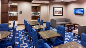 A hotel lobby with blue seating, a kitchen area, and a television on the wall. - Residence Inn by Marriott Dallas Plano/Richardson (Plano)