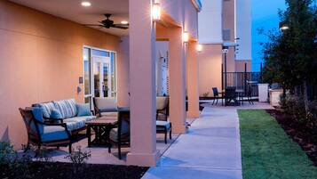 An outdoor patio area with seating, a ceiling fan, and a well-lit entrance.