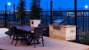An outdoor patio with a table and chairs, a grill, and a stone-built barbecue station. - Residence Inn by Marriott Dallas Plano/Richardson (Plano)