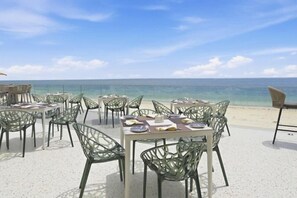 Outdoor tables and chairs on a beach with a view of the ocean. - Bamburi Beach Hotel (Mombasa)