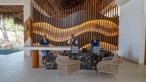En receptionsdisk med to medarbejdere, moderne design med lodrette trælameller og fletstole.