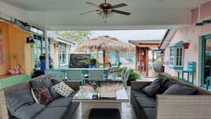 A covered outdoor seating area with wicker furniture, a ceiling fan, and a thatched umbrella. - See Sky Resort (Pak Chong)