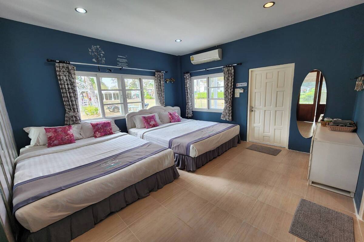 A hotel room with two beds, a white wardrobe, and a window with curtains.