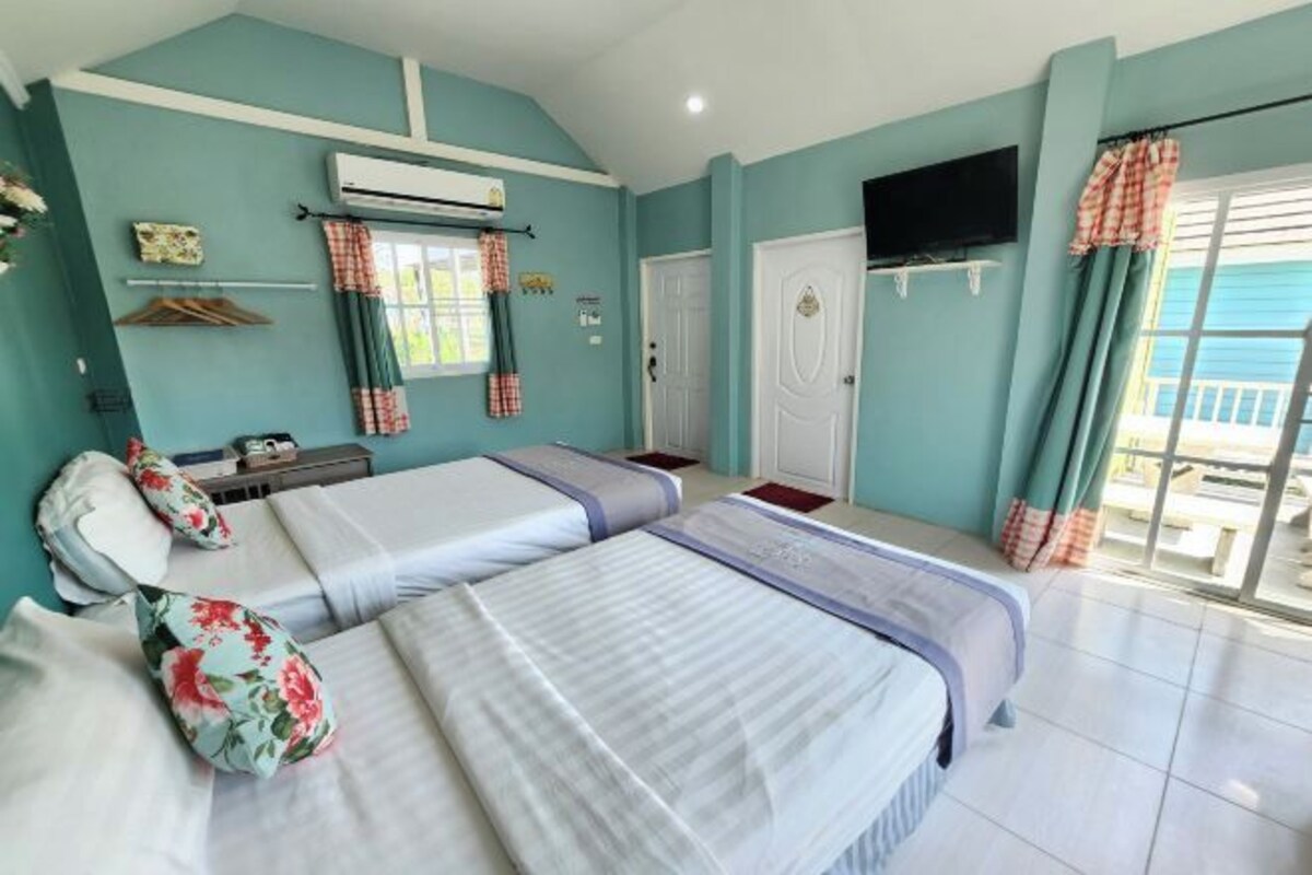 A room with two beds, a TV, and a balcony with curtains.