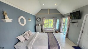 A bedroom with a large bed, a TV mounted on the wall, and a window with curtains. - See Sky Resort (Pak Chong)