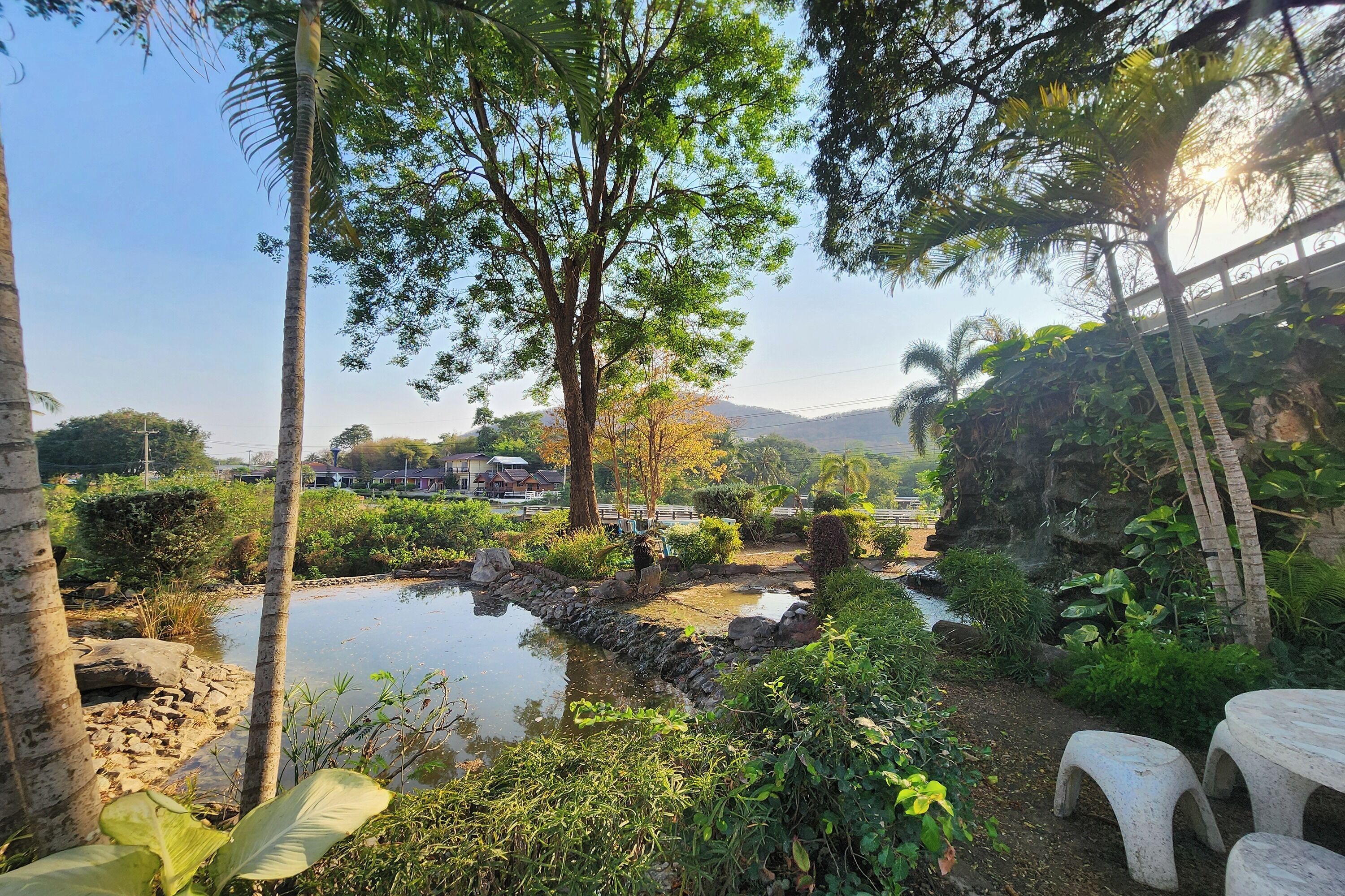A serene garden with a pond, stone pathway, and seating area.