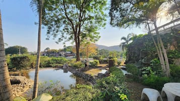 A serene garden with a pond, stone pathway, and seating area.