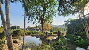 A serene garden with a pond, palm trees, and a stone bridge. - See Sky Resort (Pak Chong)