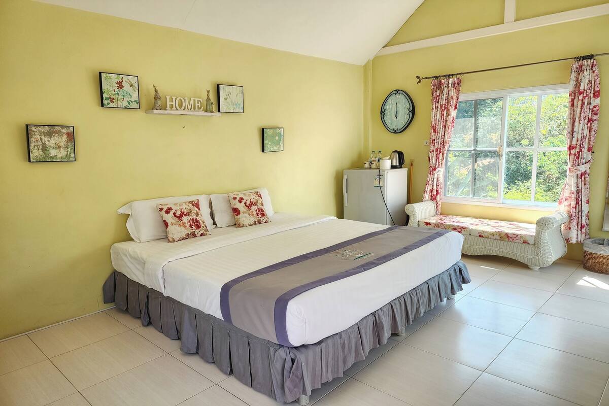 A bedroom with a bed, a window with curtains, a clock, and wall decorations.