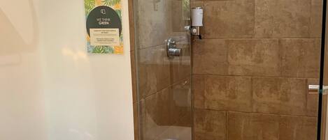 A bathroom with a glass-enclosed shower, a toilet, and a towel on the floor.