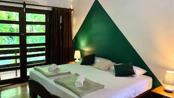 Habitación de hotel con cama, dos mesitas de noche, una lámpara y vistas a través de una ventana con cortinas.