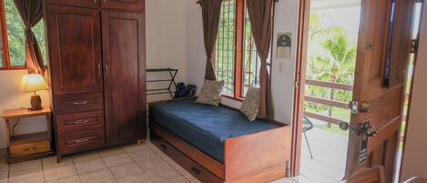A bedroom with a bed, wooden wardrobe, and a small table with a lamp.