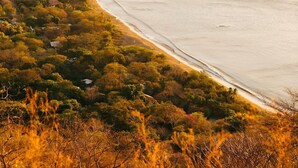 A coastal landscape with a beach, boats, and a hilly background. - Hotel Villa Del Sol (Sardinal)