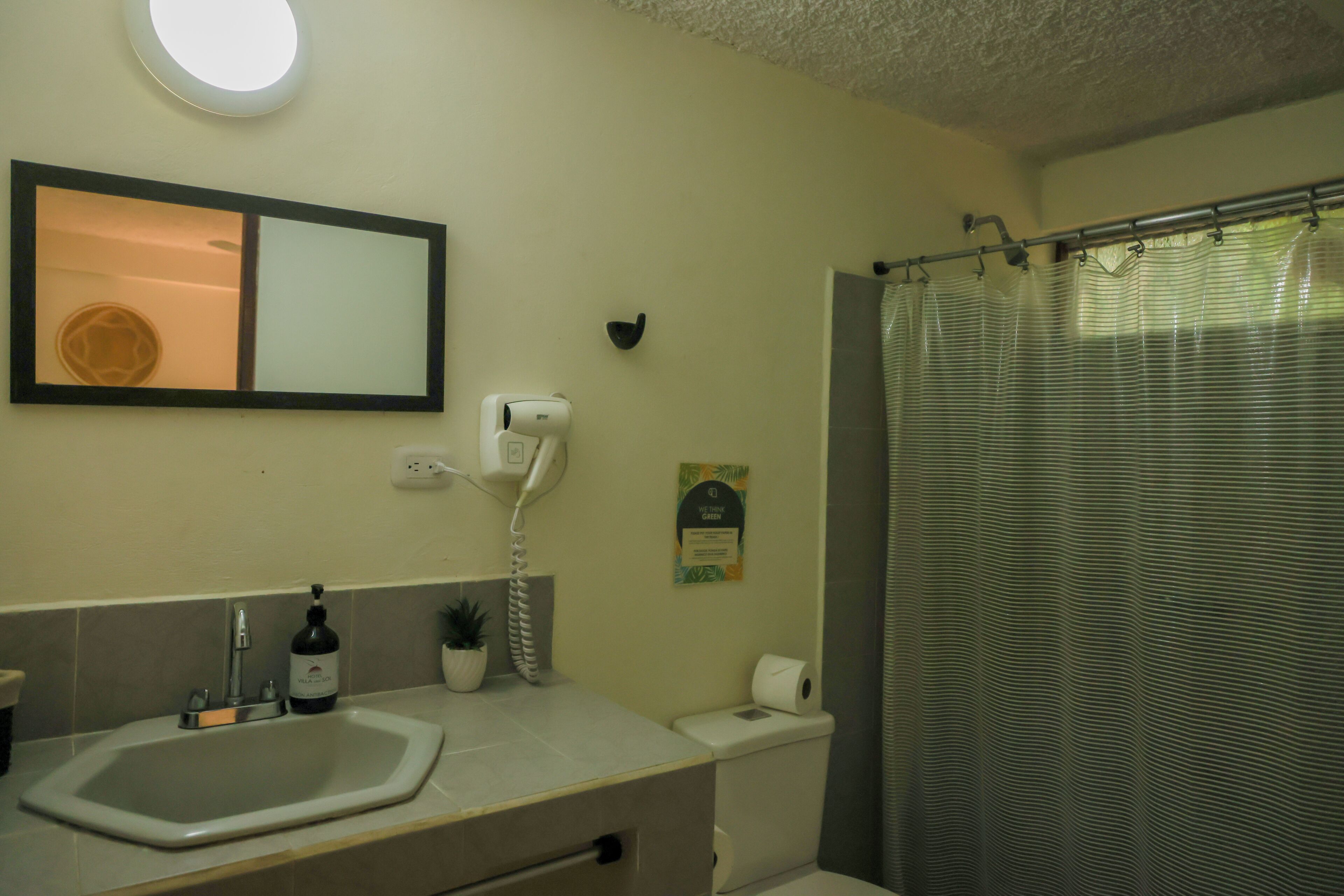 A bathroom with a sink, mirror, toilet, and shower curtain.