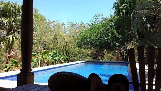 A pool area with a view of lush greenery and a clear blue sky. - Cabinas Cigalou Tamarindo (Tamarindo)