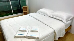 A bedroom with a bed, pillows, and folded towels. - Banana House Pai (Pai)