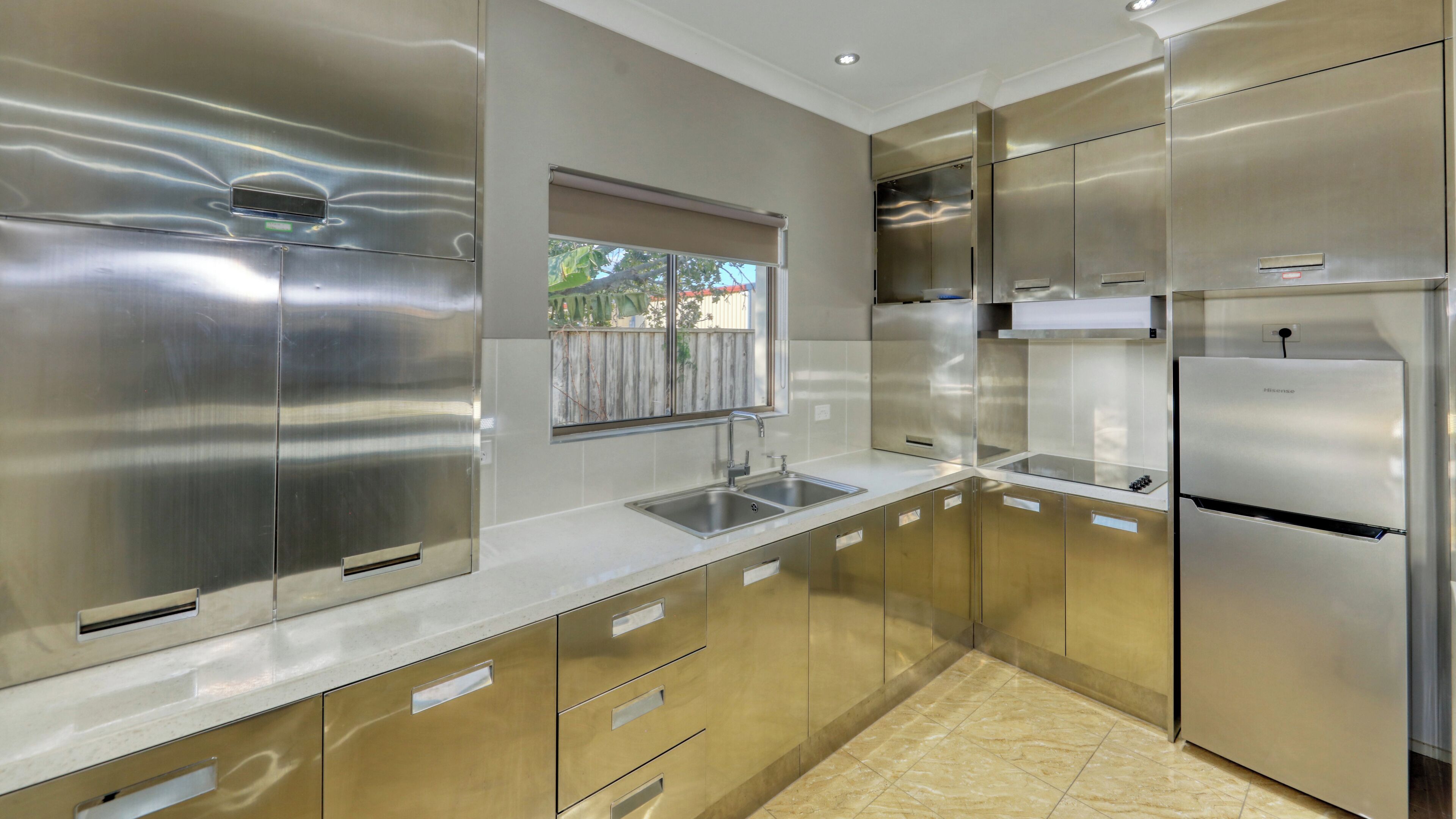A modern kitchen with stainless steel appliances, a double sink, and a window with a view of the outdoors.