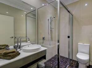 Une salle de bain moderne avec une douche à parois de verre, un lavabo blanc et des toilettes.