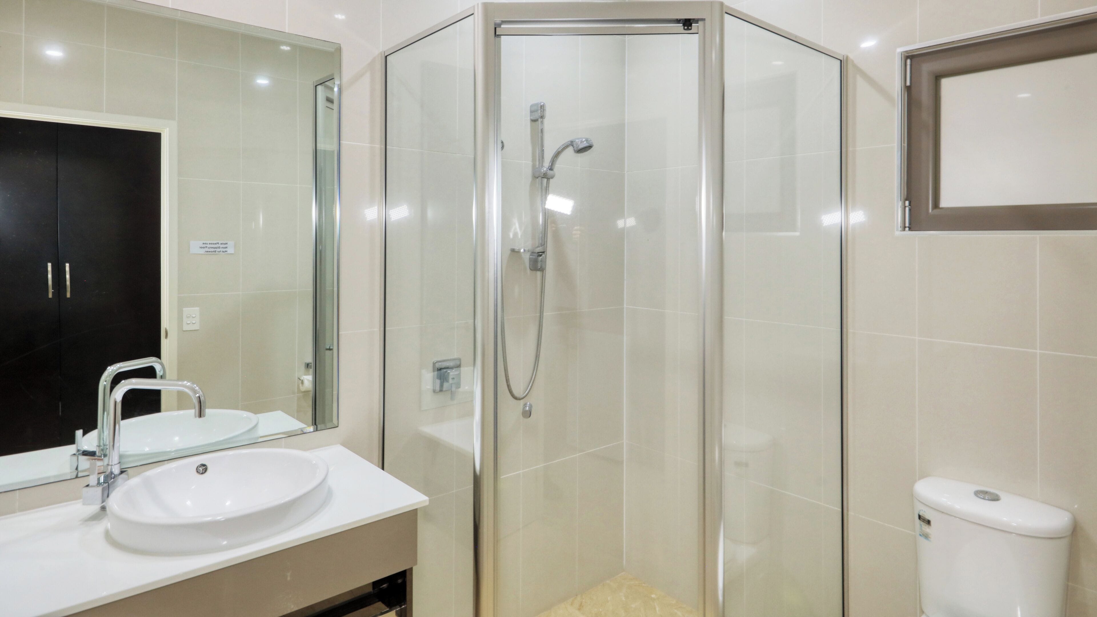 Une salle de bain moderne avec une douche à parois de verre, un lavabo avec un miroir et des toilettes.