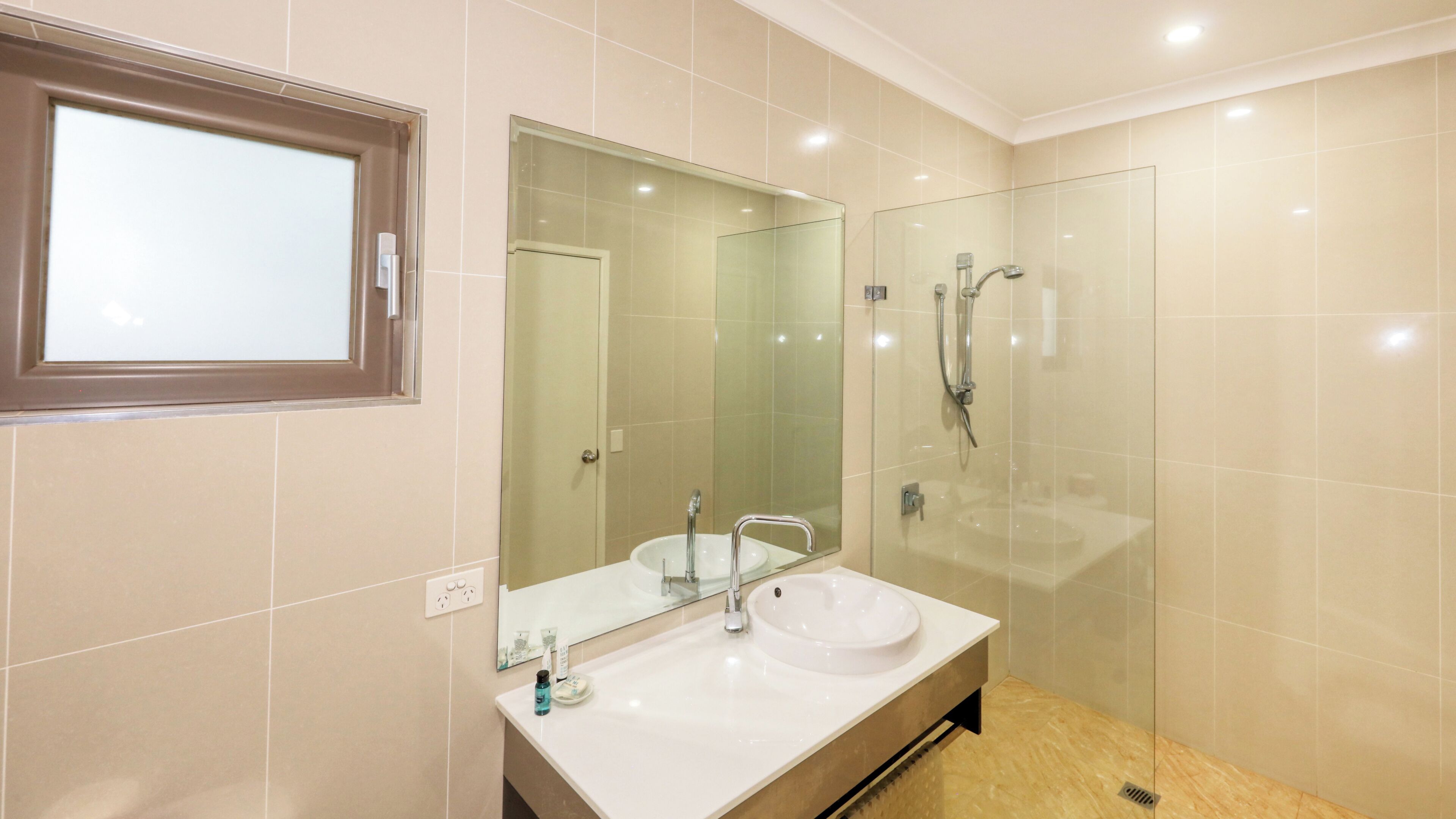 A bathroom with a double sink, a large mirror, and a glass-enclosed shower area.