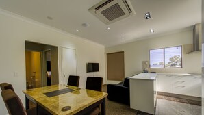 Une chambre d’hôtel moderne dotée d’un coin repas, d’une télévision et d’une grande fenêtre.