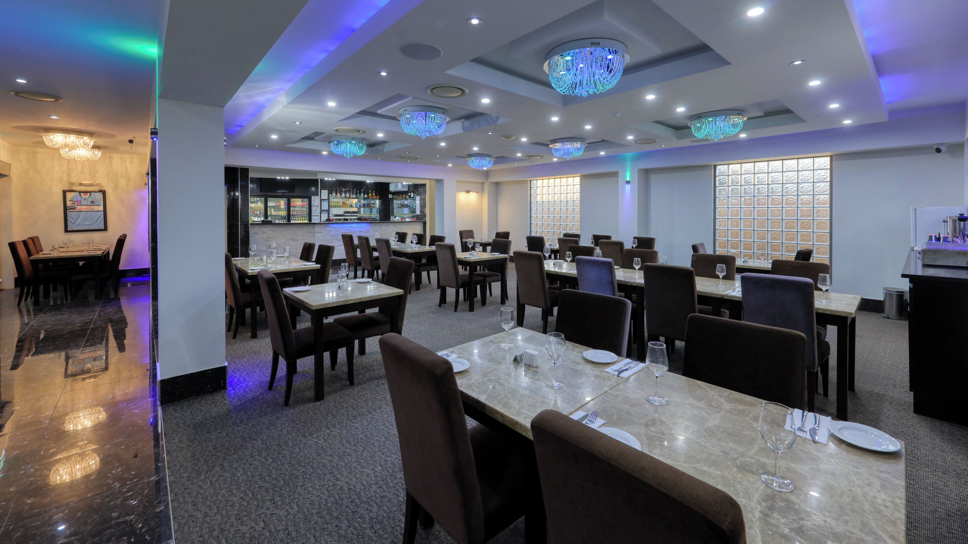 A restaurant with multiple dining tables, chairs, and a bar area.