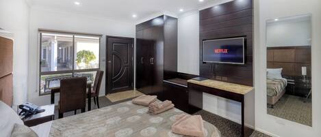 Una habitación de hotel con cama, escritorio, televisor, silla, ventana y puerta.