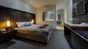 Une chambre d’hôtel moderne avec un grand lit, une table de chevet, une lampe et un bureau avec une chaise.